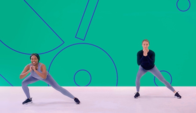 Two girls perform side lunges in an exercise class as part of a Studio You video