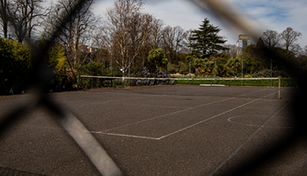 An empty tennis court captured through a wire fence.
