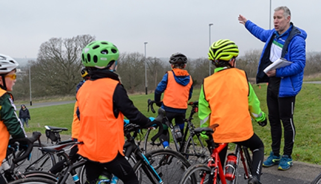 A group of young cyclists listen to their coach