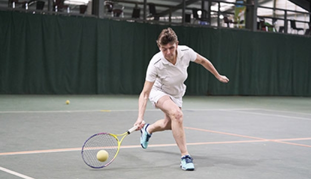 A visually impaired woman plays tennis.