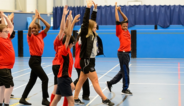 A teacher leads a group of pupils in a stretching exercise