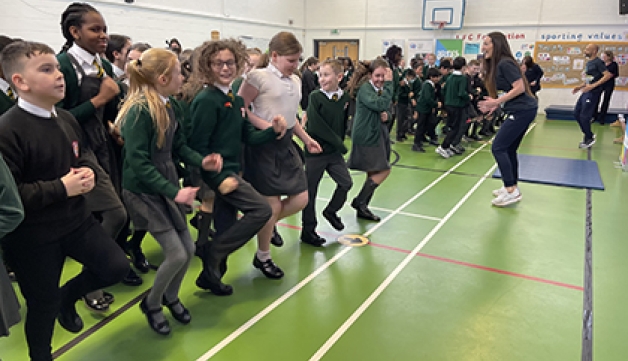 Primary school students take part in an 'Active Assembly' led by a Commonwealth Games athlete as part of a School Games initiative