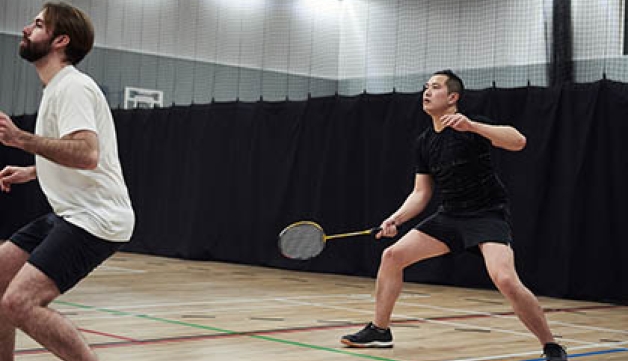 Two men receive the shuttlecock when playing badminton doubles