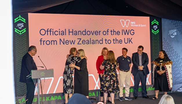 Delegates embrace on stage as the IWG on Women and Sport is handed over from Aotearoa New Zealand to the UK at an event at the Birmingham 2022 Commonwealth Games