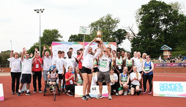 A group of athletes at the 2022 School Games National Finals celebrate and hold a trophy aloft