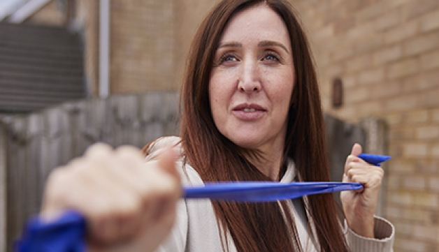 A woman exercising with a resistance band in her garden