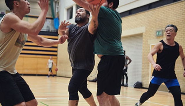 Four men play basketball in a sports hall
