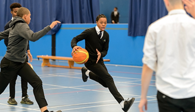 Teenage boys play basketball in school uniform in a sports hall
