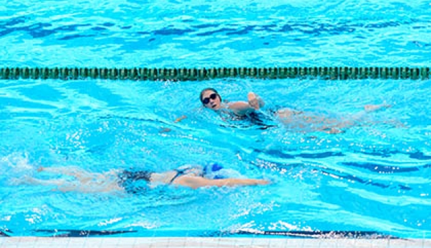 Two people swim lengths in a swimming pool