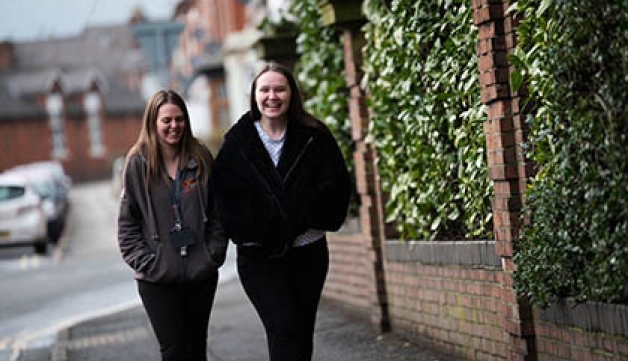 Two young women laugh as they walk down a street