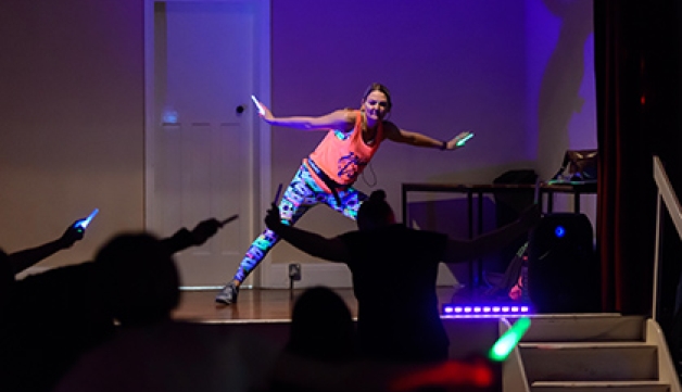 An instructor leads a neon, glow in the dark, dance fitness class