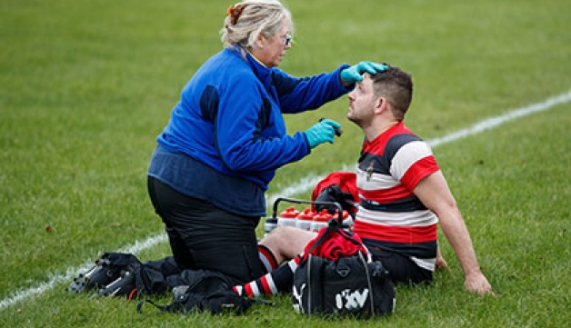 A medic tests a rugby player for concussion at the side of the pitch