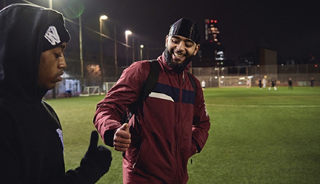 Two men fist-bump as they walk onto a 4G pitch to play football