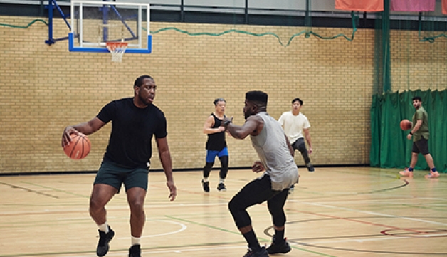 Two men play basketball in a sports hall