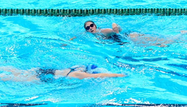 Two swimmers pass each other in a public pool 