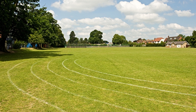 A playing field with a grass running track on it