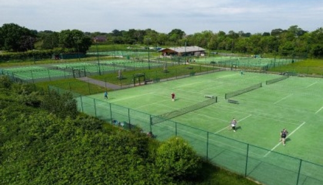 Aerial view of several courts at a tennis club, surrounded by trees