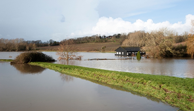 A flooded cricket pitch and pavilion after a river burst its banks.