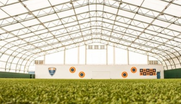 Grass-level shot of an indoor football pitch.