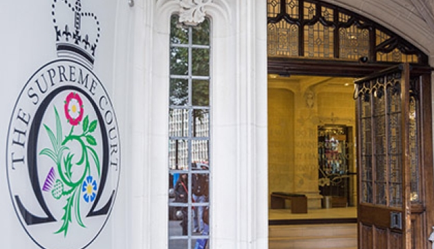 A general view of the UK Supreme Court, with the logo on the left side of the door, and the door open, looking in