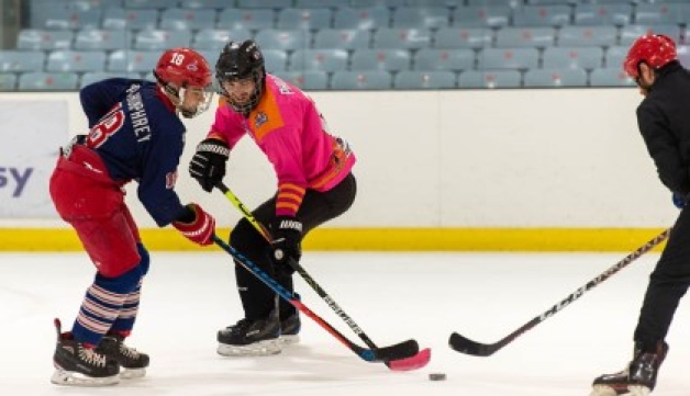 Three ice hockey players compete for the puck.