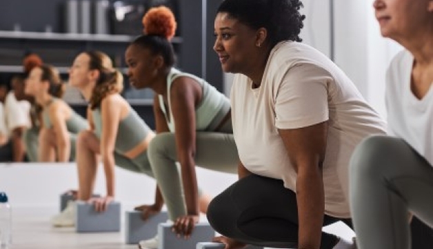 A row of women lunging with blocks in a fitness class.