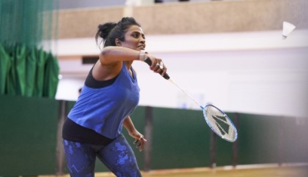 A woman playing badminton in a sports hall.