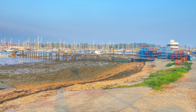 A view from the shore of a jetty, water and boats at Warsash Sailing Club.