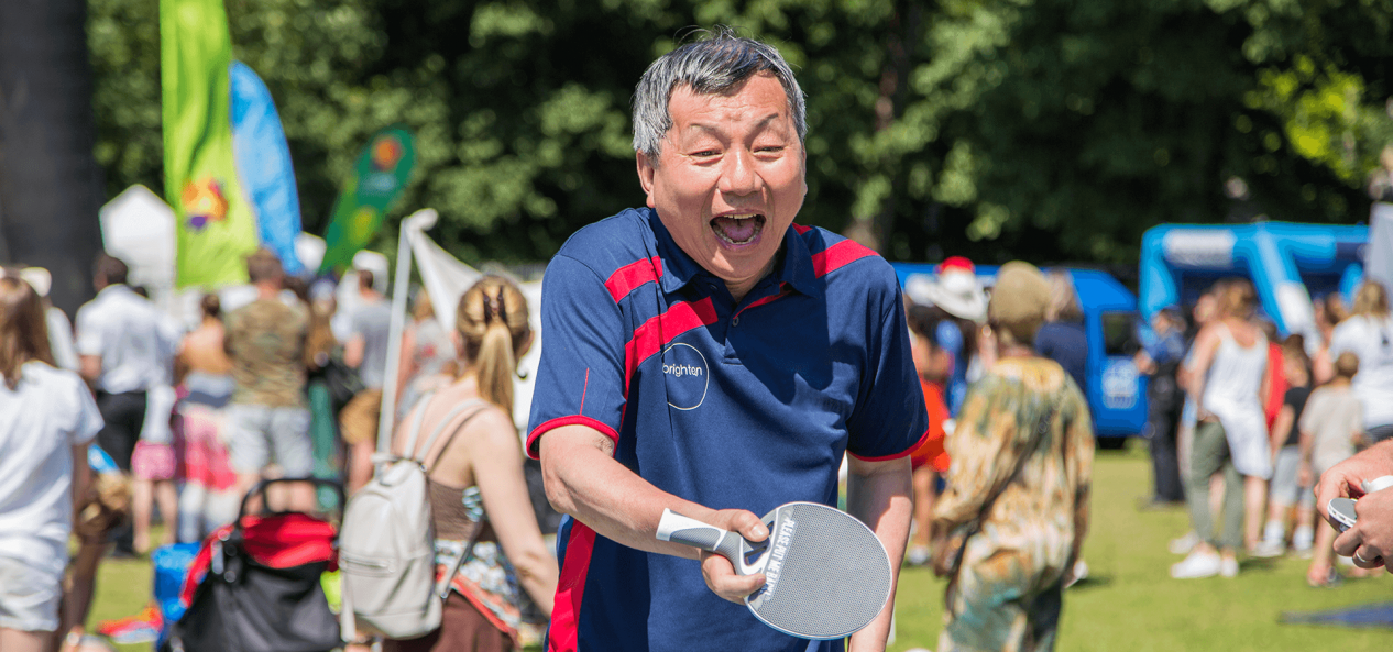 Man playing table tennis outside looking happy