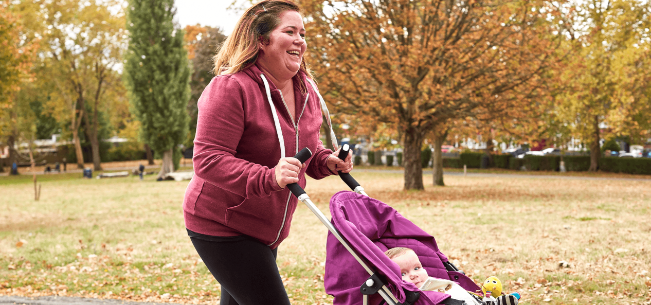 Mother walking her baby in buggy in park