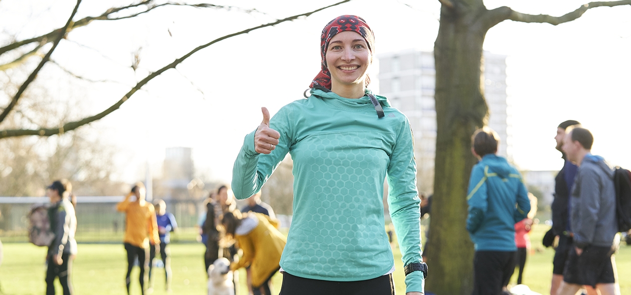 A woman gives a thumbs up to the camera after completing a parkrun