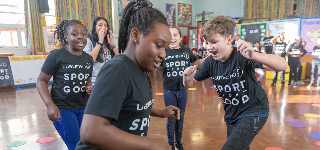Children wearing Laureus sport for good t-shirts play in a school hall