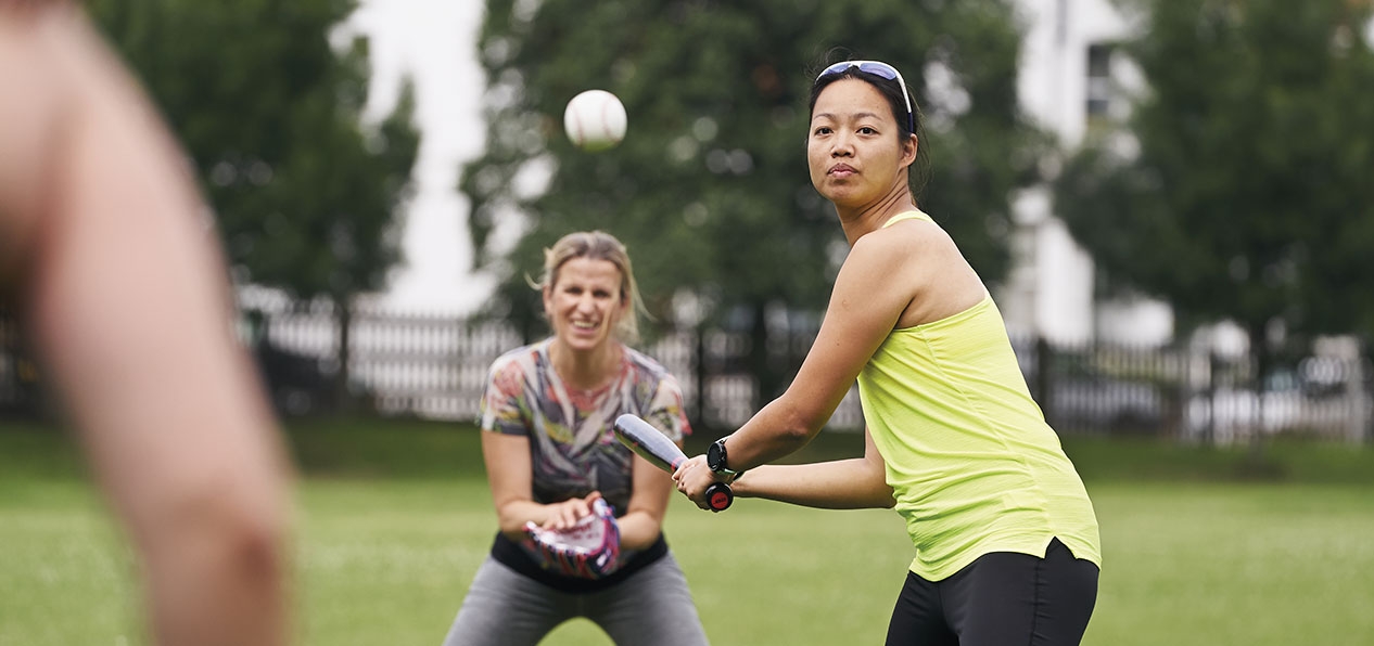 Women play rounders in a park