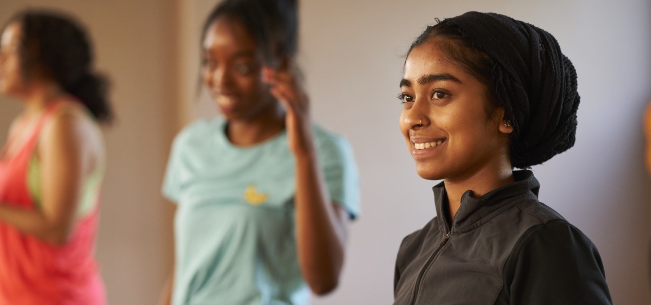 A young woman smiles during a fitness class in a studio you.