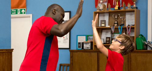Child and coach high five during table tennis game