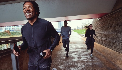 Three people jog on a path under a bypass.