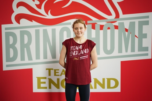 Para swimmer Poppy Maskill poses for a photo at a Team England kitting out event, infront of a Team England branded backdrop