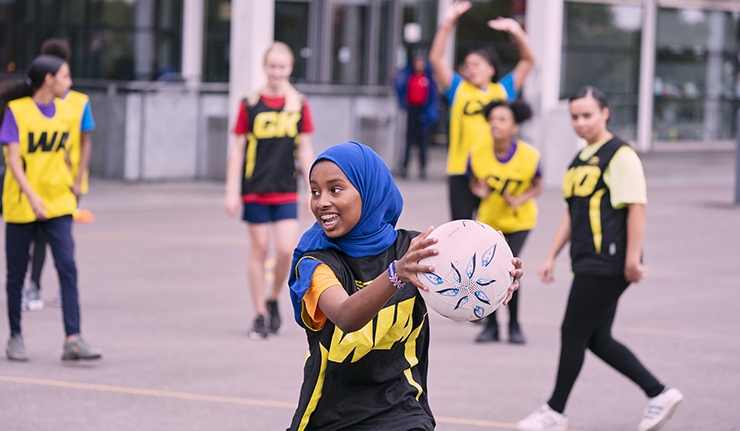 A girl playing netball on an outdoor court.
