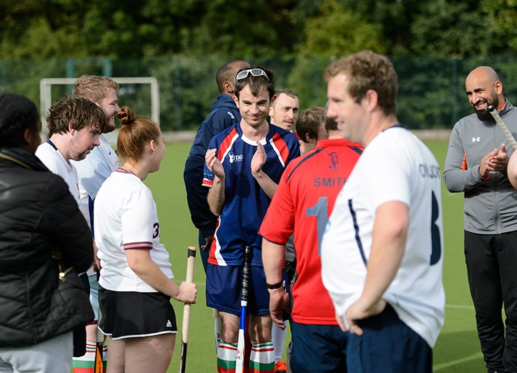 A group of hockey players talking on the field after a game.