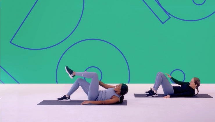 Two girls perform stretches during an exercise class for a Studio You video