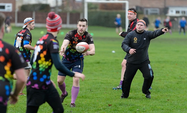 A man passes a rugby ball to his teammate during a training session.