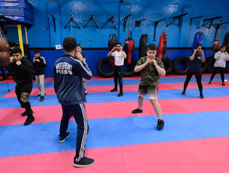 A boxing instructor leads a group of young boys through a shadow-boxing training routine