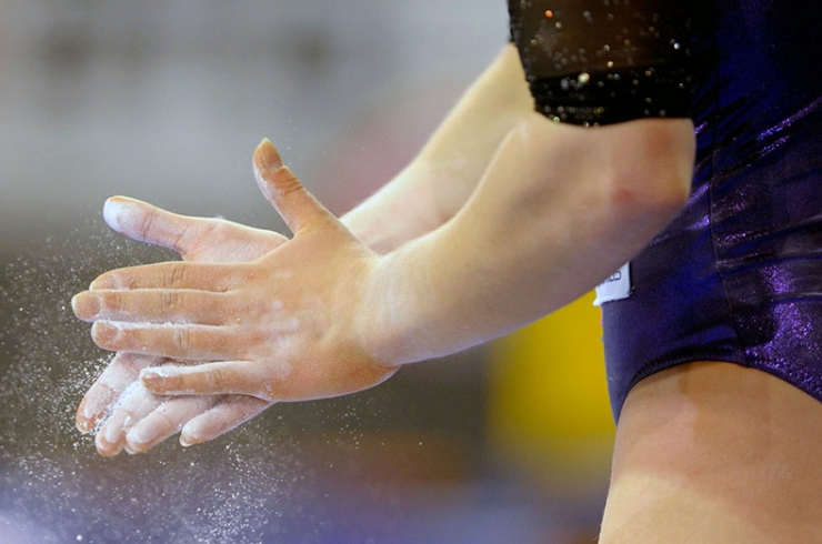 A gymnast chalks her hands