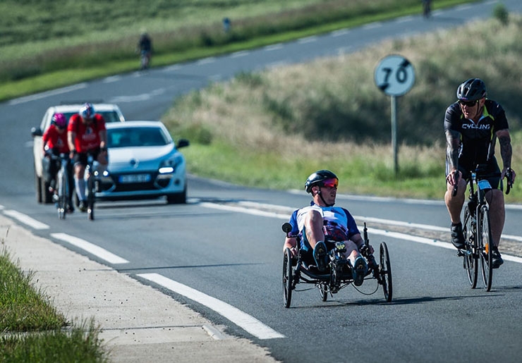 A recumbent cyclist pedals alongside an upright cyclist as part of a Help for Heroes event