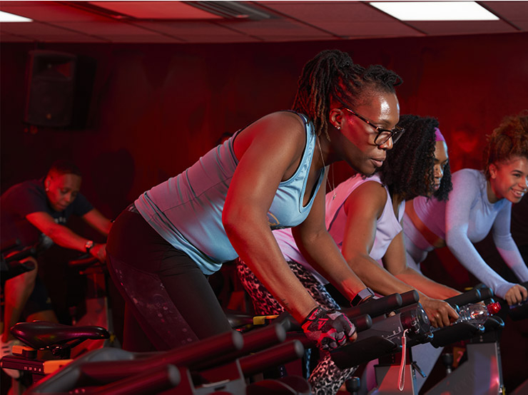 A group of women participate in a spin class in a gym