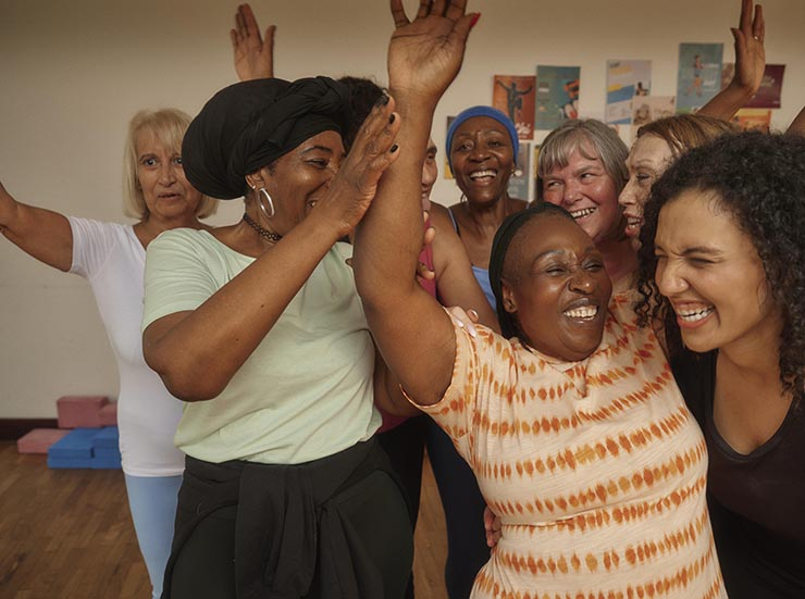 A group of women laugh, smile and dance during a group exercise class