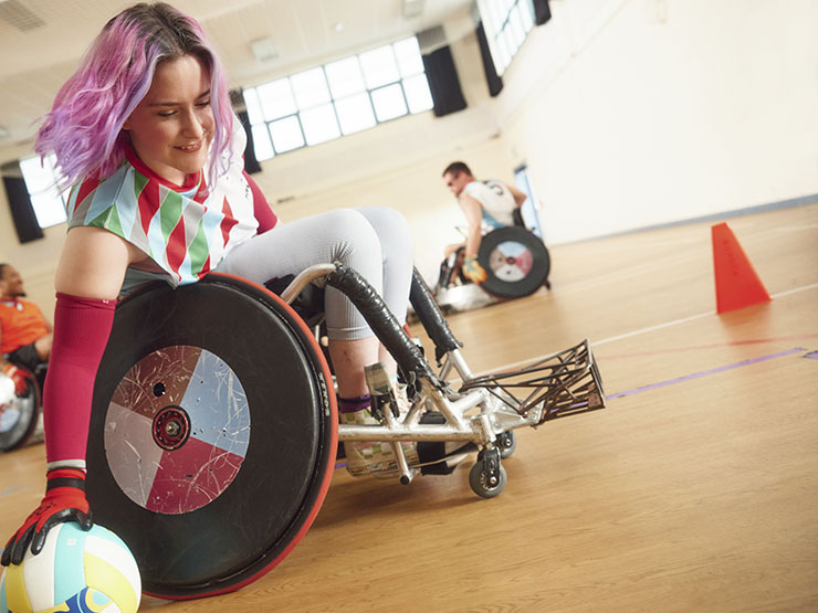 A woman with purple hair plays wheelchair rugby