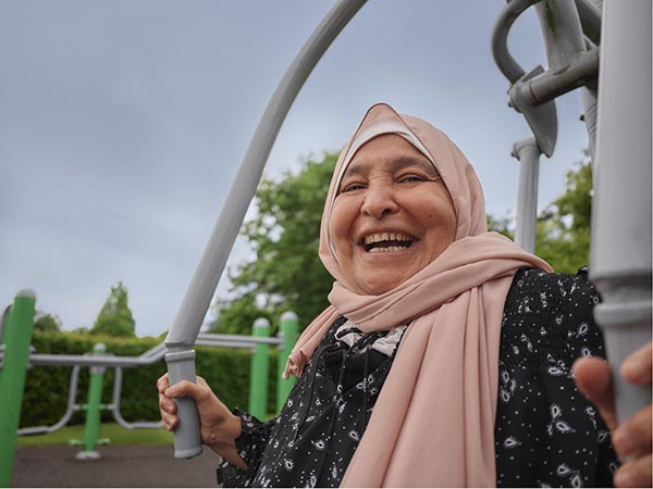 A woman wearing a headscarf uses a chest press machine in a park gym