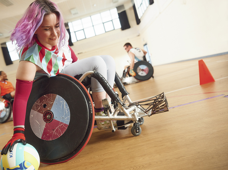 A woman with purple hair plays wheelchair rugby
