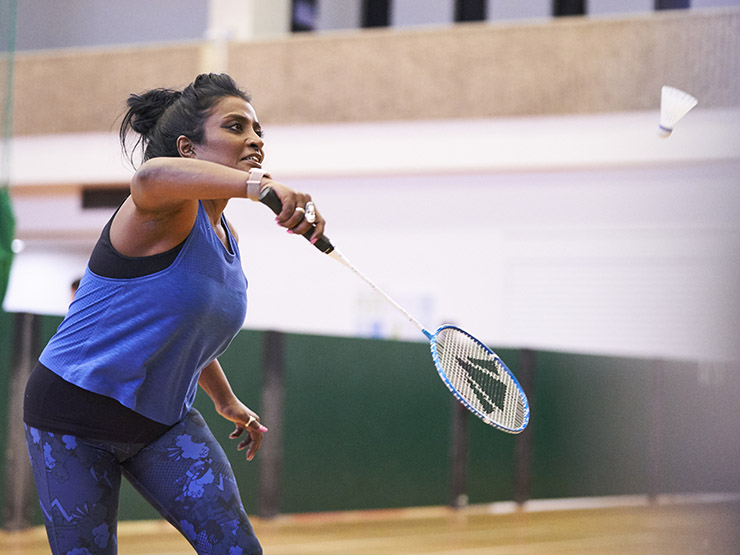 A woman plays badminton in a hall